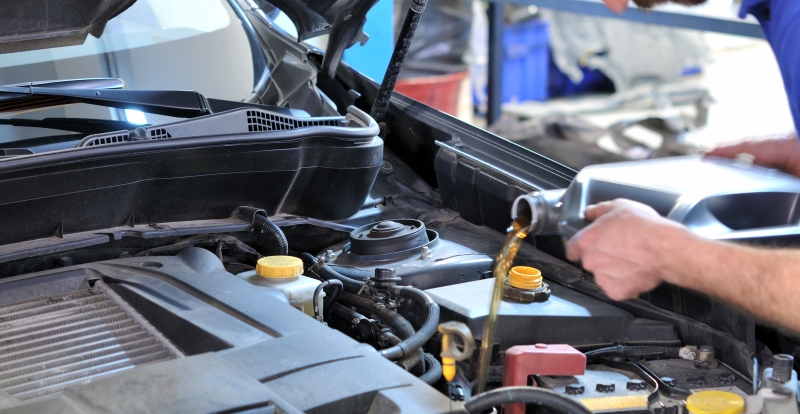 Car mechanic changing oil - model and oil motion blurred.